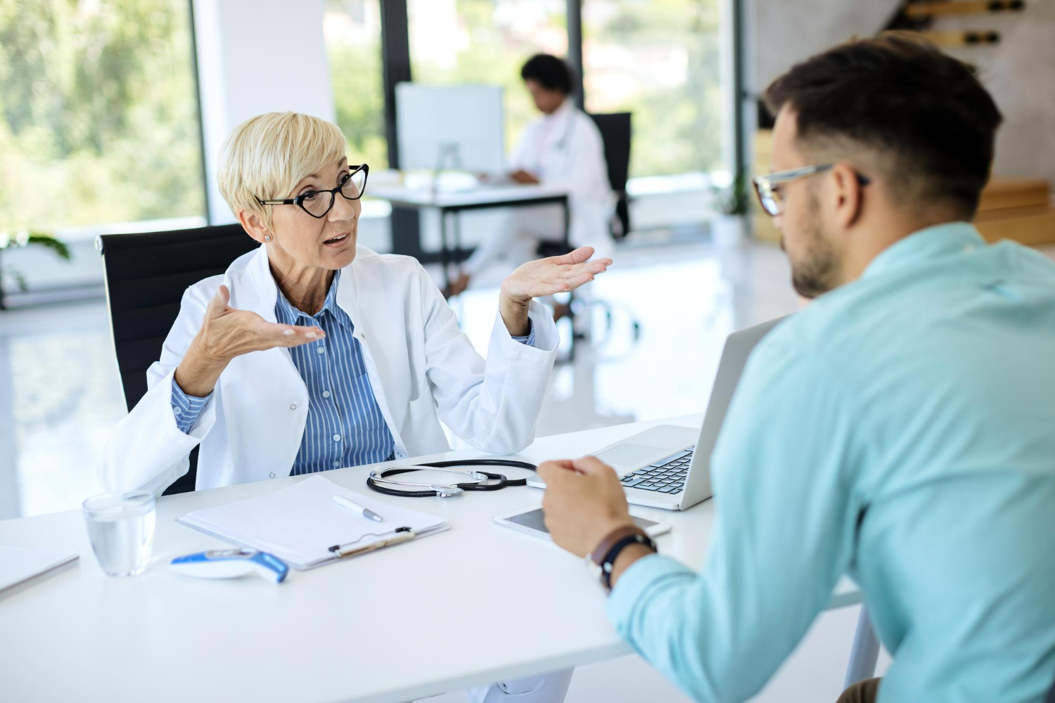 Female doctor explaining to paitent with stethescope in table